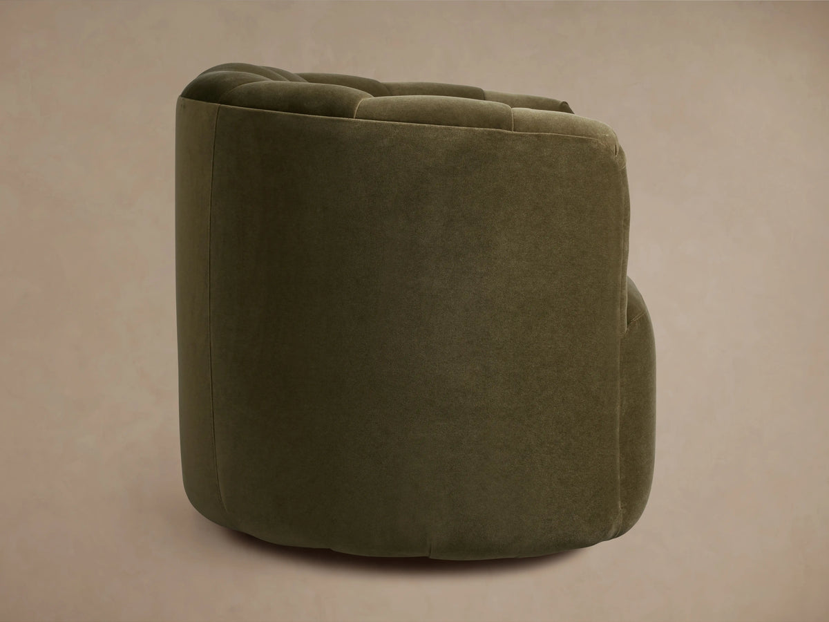 Amira Swivel Chair close-up: dark olive green velvet upholstery with deep, soft pleats on the back and armrest.
