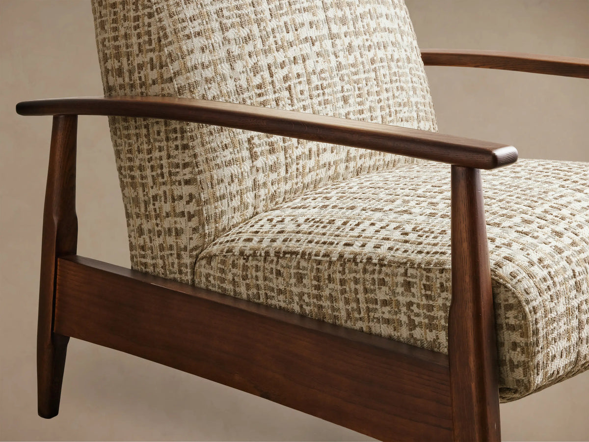 Close-up of beige and brown textured weave pattern on an armchair with dark wooden armrests and frame, angled.