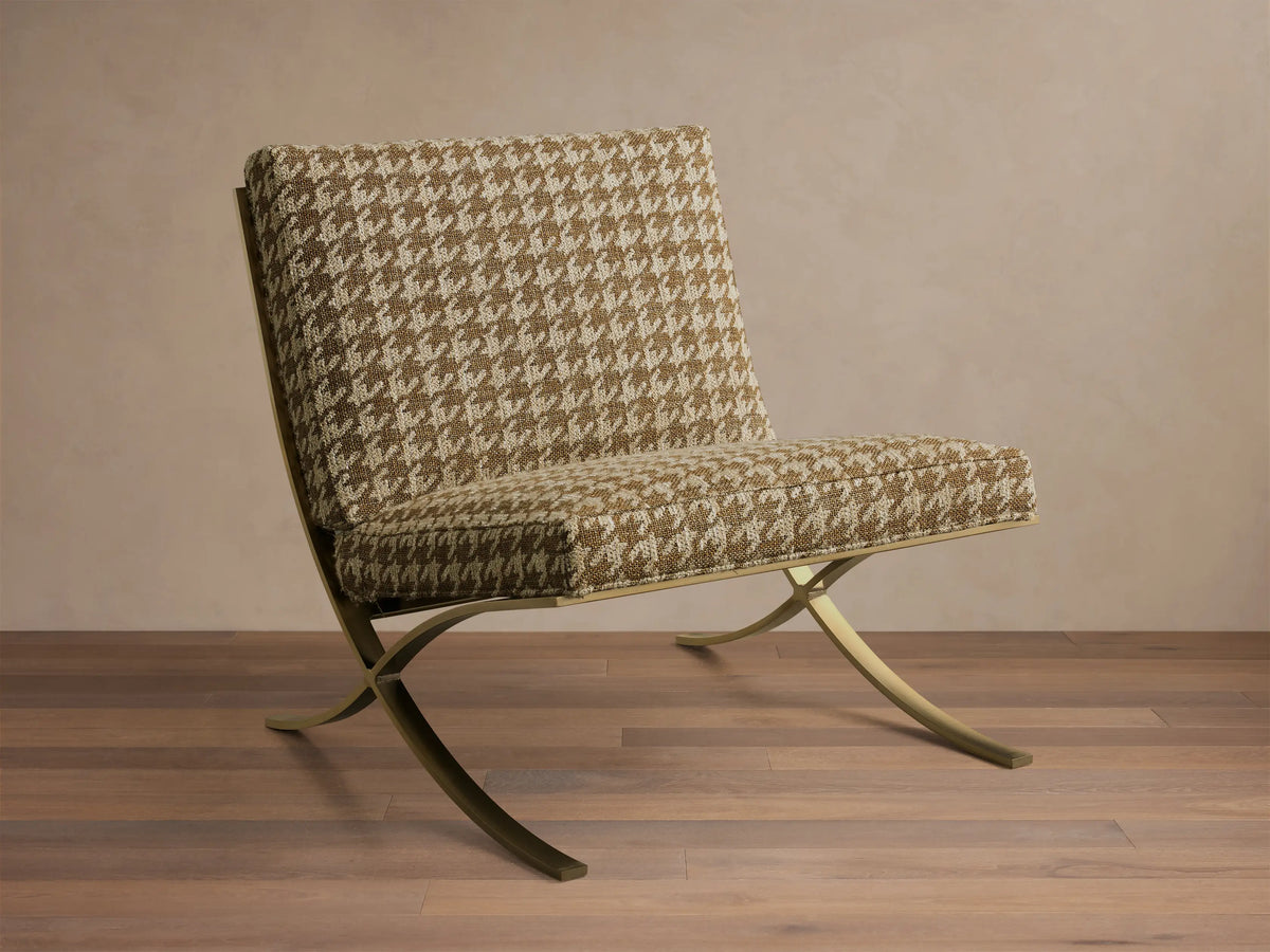 Front view of the Moxie Chair with brown and beige houndstooth upholstery and gold-toned finished stainless steel X-legs.