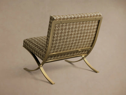 Rear view of the Moxie Chair, featuring tan houndstooth upholstery and a curved, exposed brass frame.