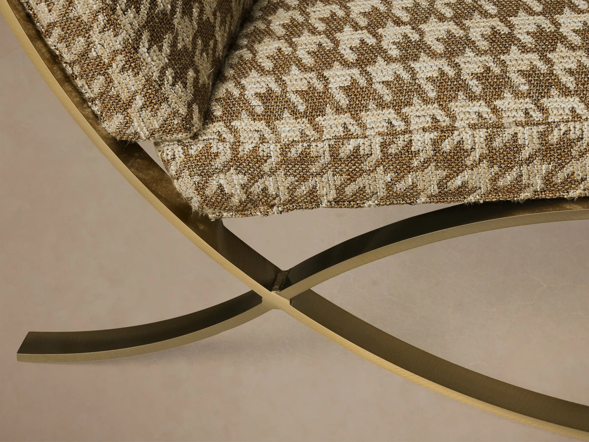 Close-up of the Moxie Chair showing its brown and beige houndstooth cushion with a gold metallic curved base.