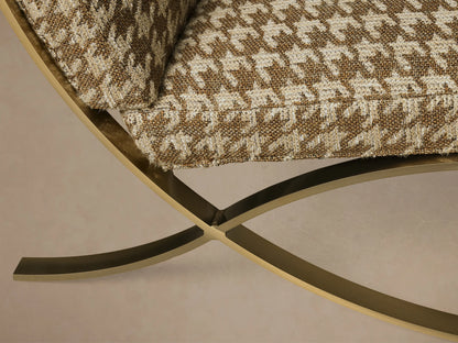 Close-up of the Moxie Chair showing its brown and beige houndstooth cushion with a gold metallic curved base.