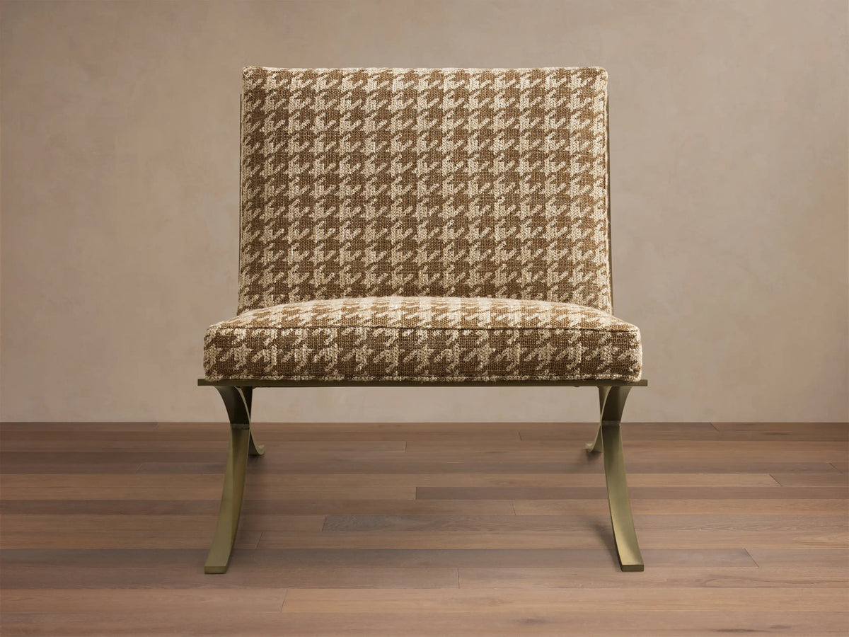 Front view of the Moxie Chair with brown and beige houndstooth upholstery and gold-toned finished stainless steel X-legs.