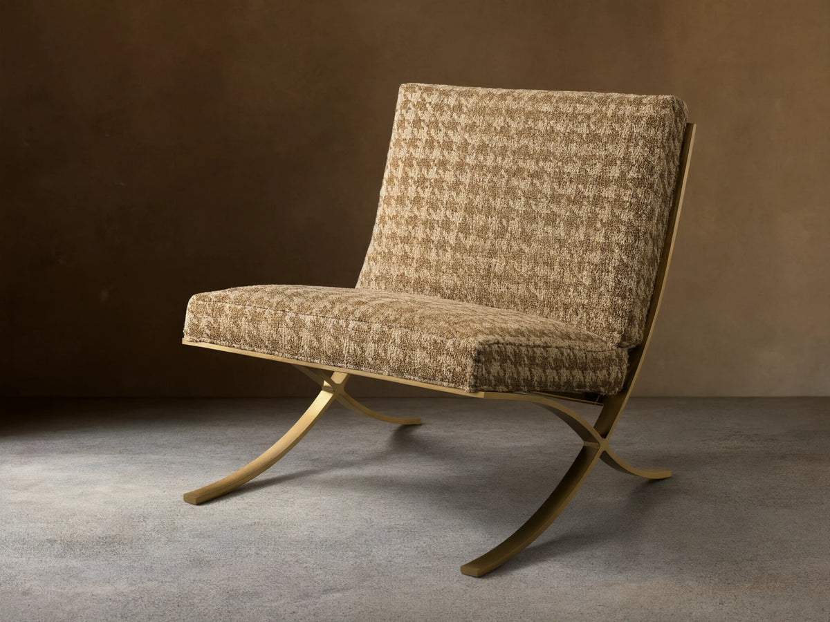 Front view of the Moxie Chair with brown and beige houndstooth upholstery and gold-toned finished stainless steel X-legs.