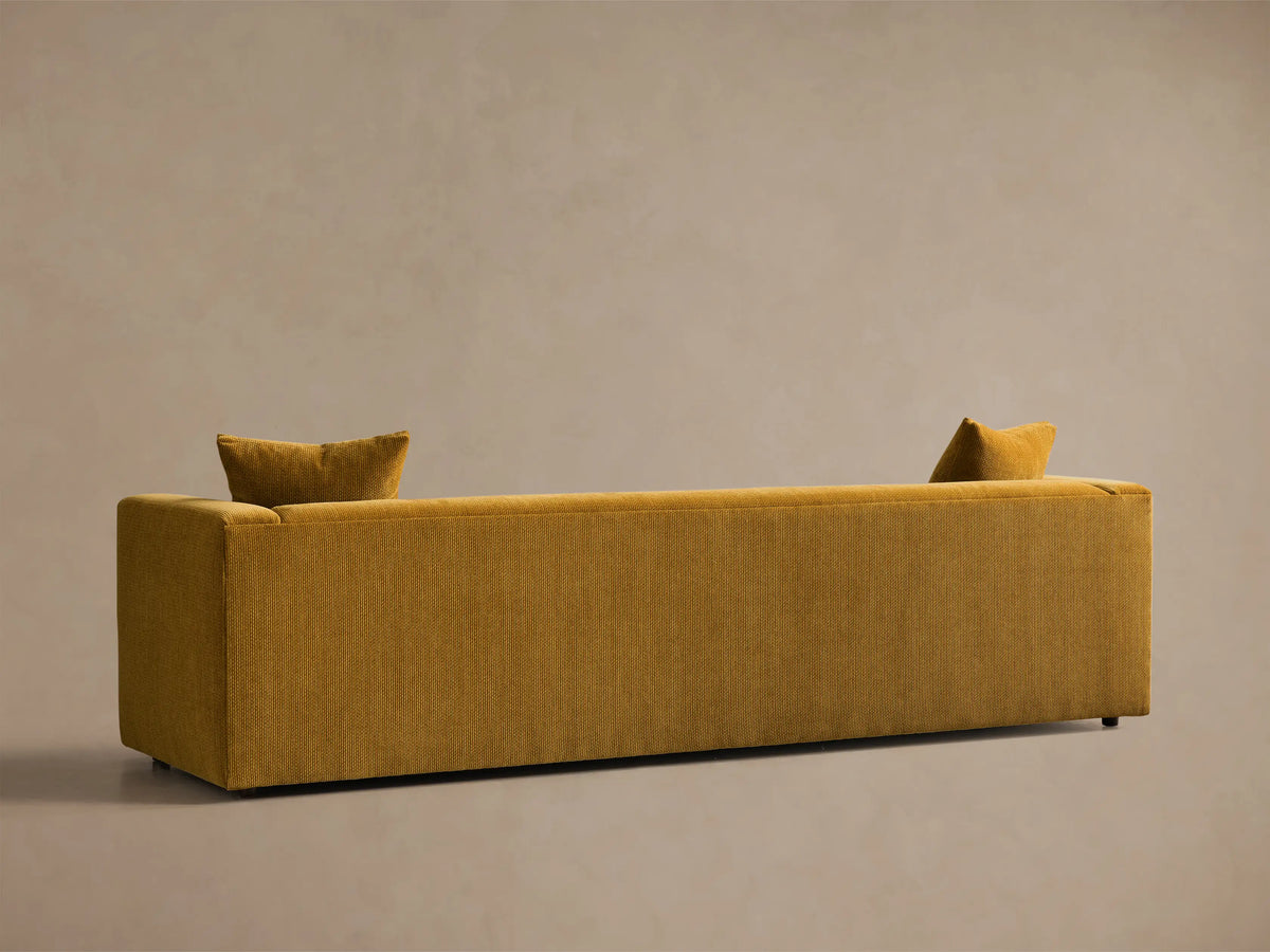Rear view of the mustard yellow textured fabric Brady Sofa, with two small pillows over the back.