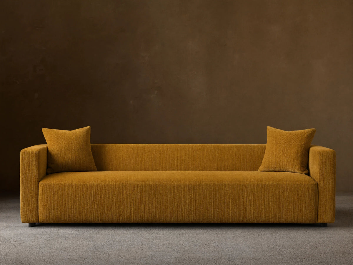 Front view of the mustard yellow Brady Sofa, a contemporary design with two matching throw pillows.
