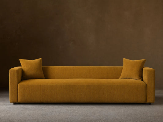 Front view of the mustard yellow Brady Sofa, a contemporary design with two matching throw pillows.