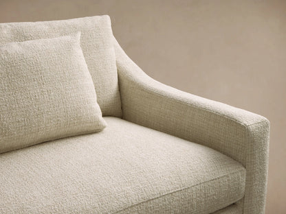 Front view of a light cream Ashby Elevated Sofa with sloped arms, two rectangular accent pillows, and mocha finish wooden legs.