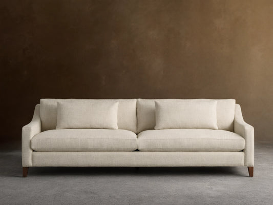 Front view of a cream Ashby Elevated Sofa with woven texture, two seat cushions, two back pillows, and dark mocha finish feet.