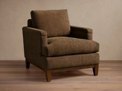 Front view of a brown textured fabric armchair with wide arms, loose cushions, and a visible dark wood base and legs.