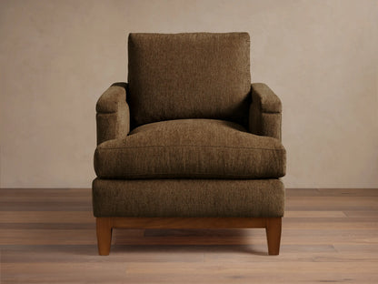 Front view of a brown textured fabric armchair with wide arms, loose cushions, and a visible dark wood base and legs.