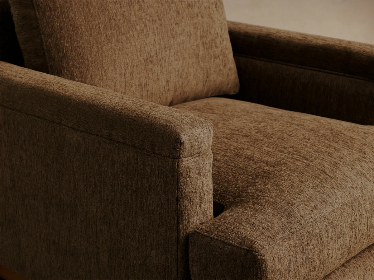 Front view of a brown textured fabric armchair with square arms and exposed light wooden legs.