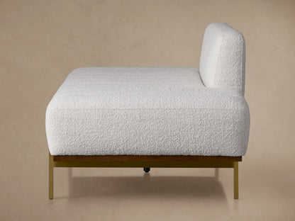 Lansing Daybed featuring a soft gray fabric, wooden base, and metal legs. Backrest central, cushions extend from sides. Beige wall background.