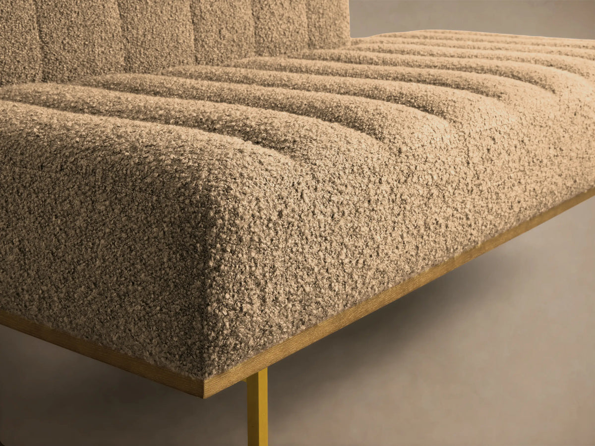 Front view of the beige bouclé Lansing Daybed with channel-tufted cushions and gold metal legs.