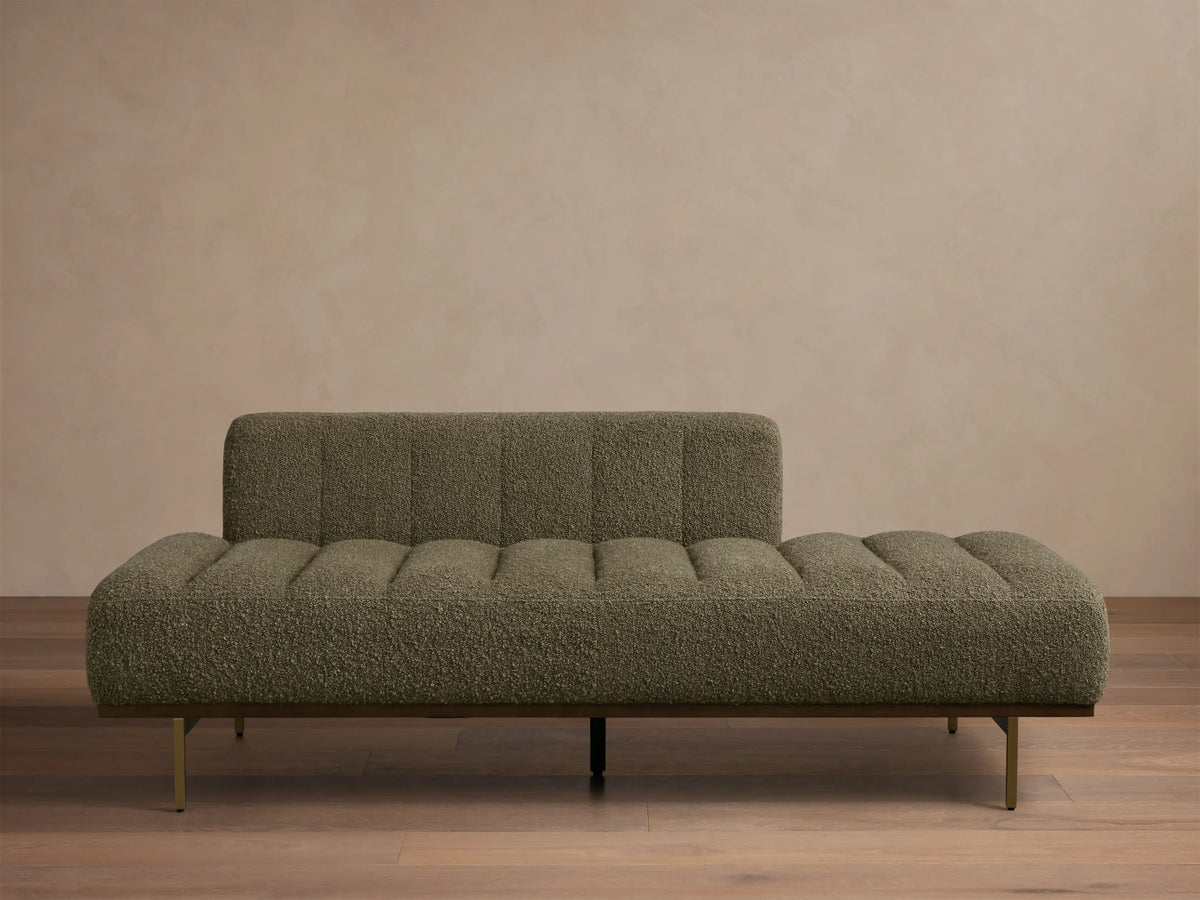 Front view of an olive green textured chaise lounge with a low back, channeled seat, and wooden base with metal legs.