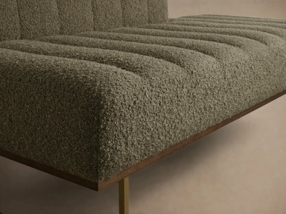 Close-up of a greige bouclv© bench, featuring ribbed upholstery on the seat and back, with a dark wood base and gold leg.