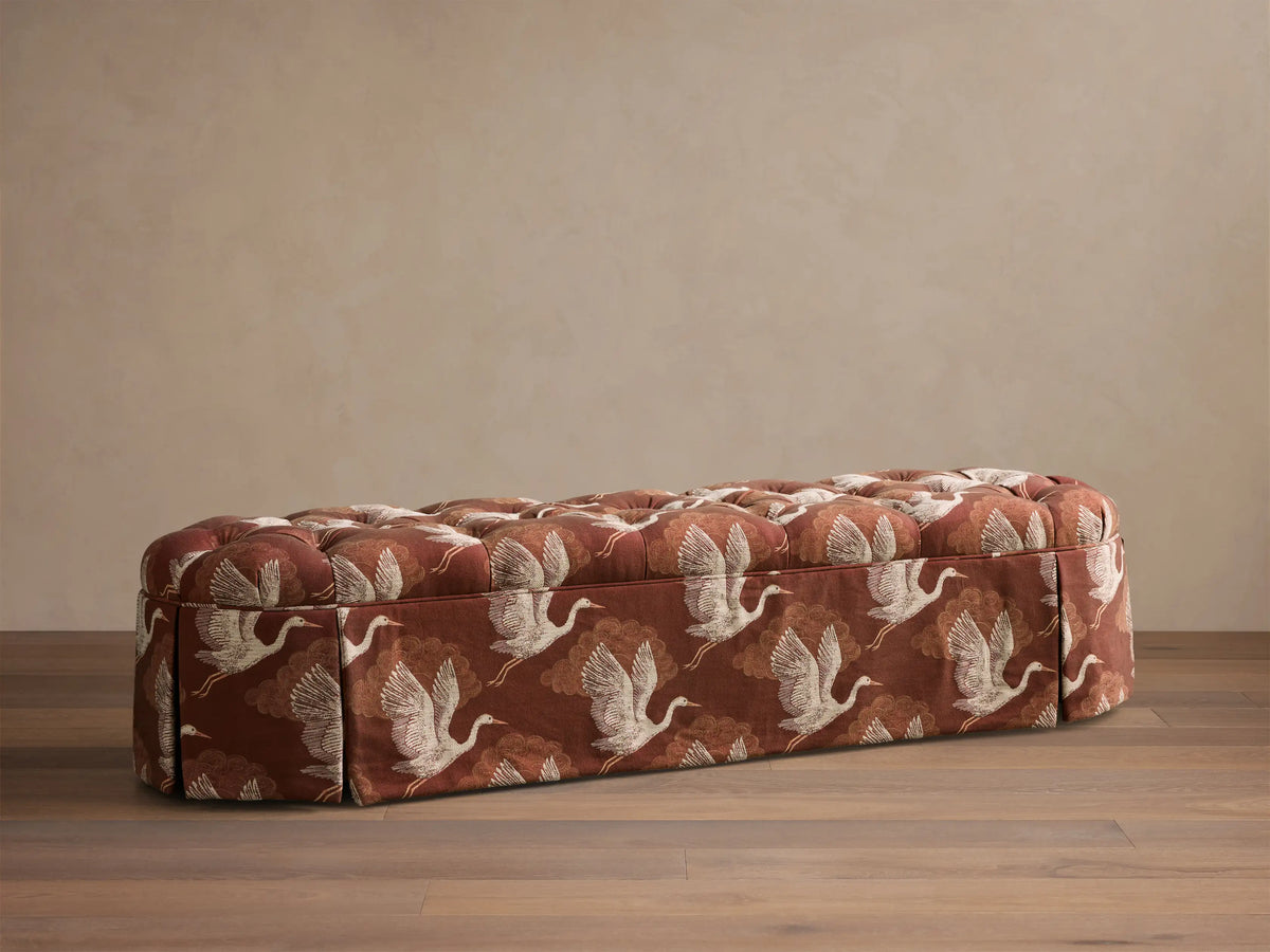 Front view of the reddish-brown Liddie Oval Bench with a tufted top and white crane and cloud pattern.