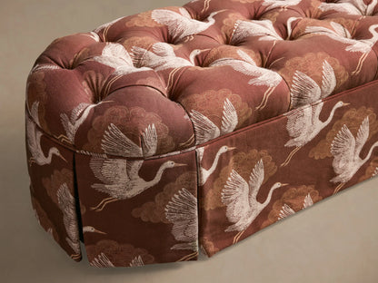 Close-up of the russet crane-patterned Liddie Oval Bench, showing its tufted top and pleated skirt.