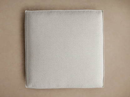 Overhead view of the light gray Coburn Ottoman, a soft square cushion with fine texture and piping along the seams.