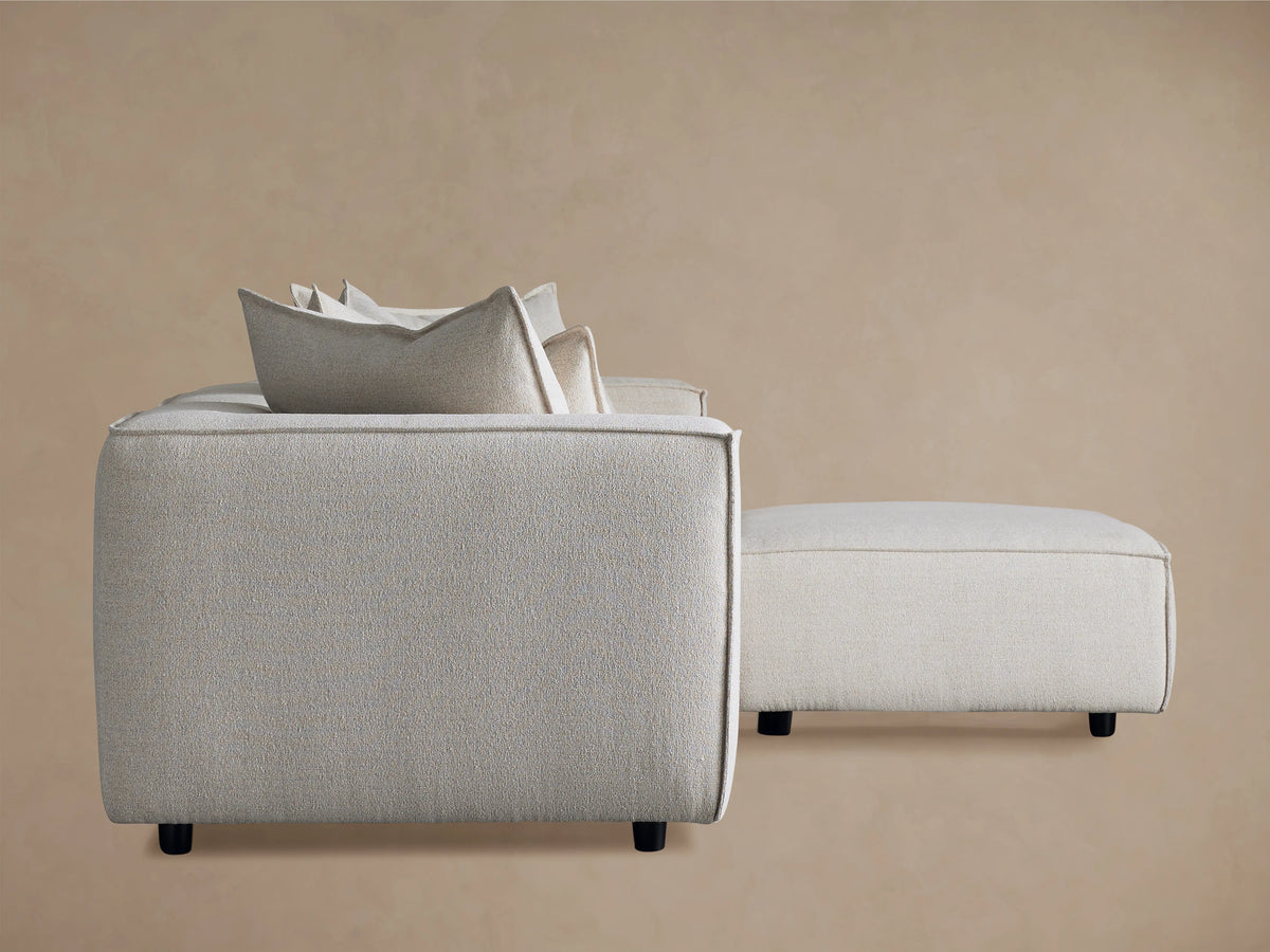 Coburn Four-Piece Sectional in light beige fabric with plush cushions and streamlined armrest, set against a neutral background.