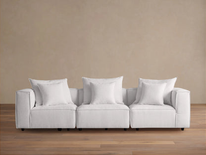 Coburn Three Piece Modular Sofa in light gray fabric, featuring three sections with plush cushions and pillows in a minimalist setting.