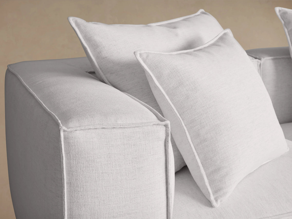 White Coburn Three Piece Modular Sofa with three sections, plush cushions, and padded armrests on a wooden floor against a neutral wall.
