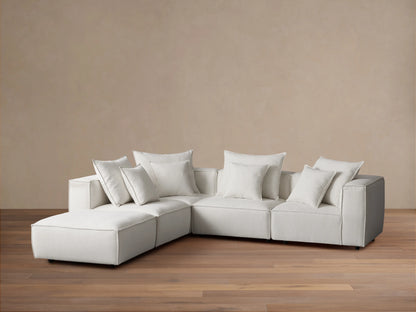 Light grey Coburn Five-Piece Sectional, L-shaped, with 7 square and rectangular back pillows, on wood floor.