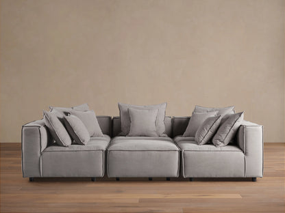 Gray Coburn Six-Piece Pit Sectional on wooden floor, with plush back and seat cushions and multiple pillows, set against a neutral wall.