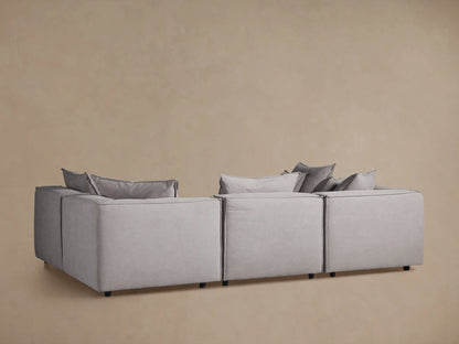 Coburn Six-Piece Pit Sectional in a neutral gray fabric with plush back pillows, block design, and wooden floor setting.