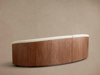 Rear view of the Caden Two-Piece Sectional, featuring a curved design with walnut wood veneer and light textured upholstery.