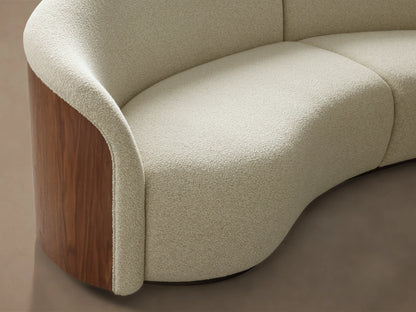 Front view of the curved Caden Two-Piece Sectional, upholstered in cream textured fabric with dark walnut wood veneer sides.