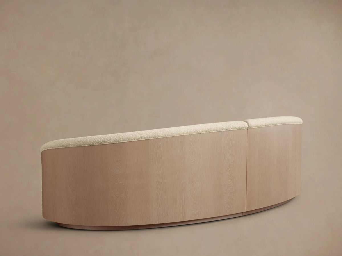 Rear view of the curved Caden Two-Piece Sectional with sand finish oak veneer base and cream upholstered back.