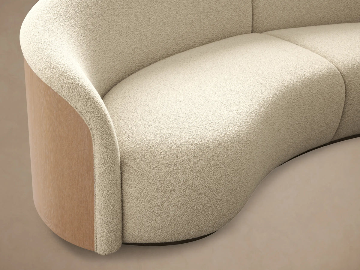 Front view of cream Caden Two-Piece Sectional, curved with textured fabric, sand veneer, and brushed nickel plinths.
