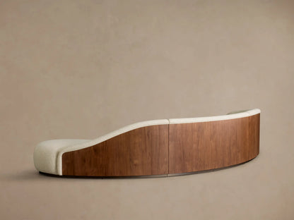 Rear view of the curved Caden Three-Piece Bumper Sectional with cream upholstery and walnut wood veneer panels.