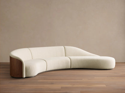 Front view of the cream Caden Three-Piece Bumper Sectional, with a curved design, walnut wood side panel, and chaise bumper.