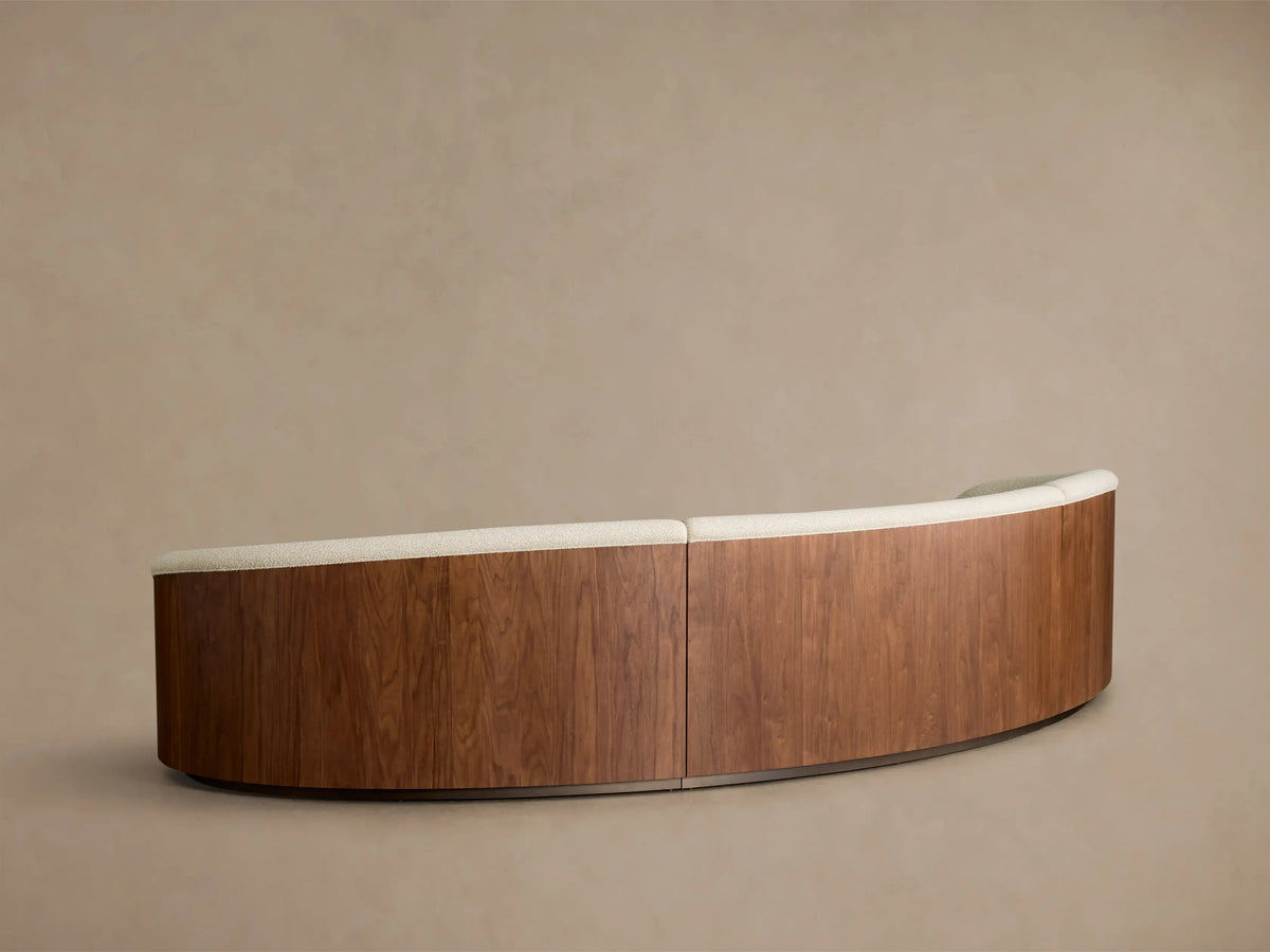 Front view of an off-white Caden Three-Piece Sectional with a curved design, upholstered in textured fabric and dark walnut veneer side panels.