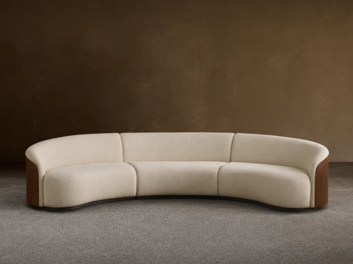 Front view of an off-white Caden Three-Piece Sectional with a curved design, upholstered in textured fabric and dark walnut veneer side panels.