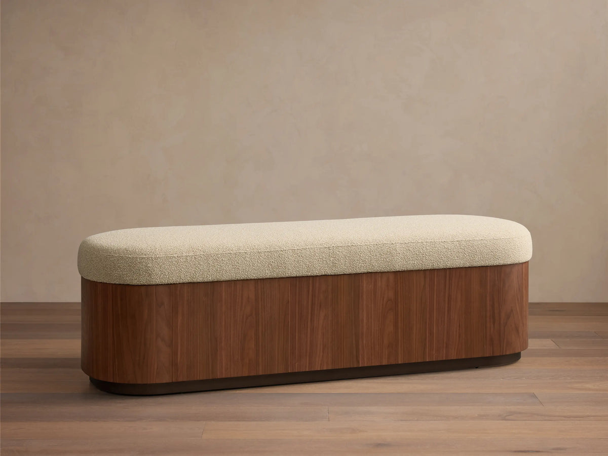 Front view of the Caden Storage Bench, with an elongated light beige textured top and a walnut wood base.