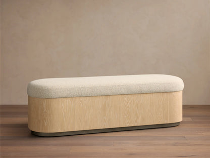 Front view of the Caden Storage Bench, featuring a cream textured cushion and an elongated sand oak veneer base with a dark gray plinth.