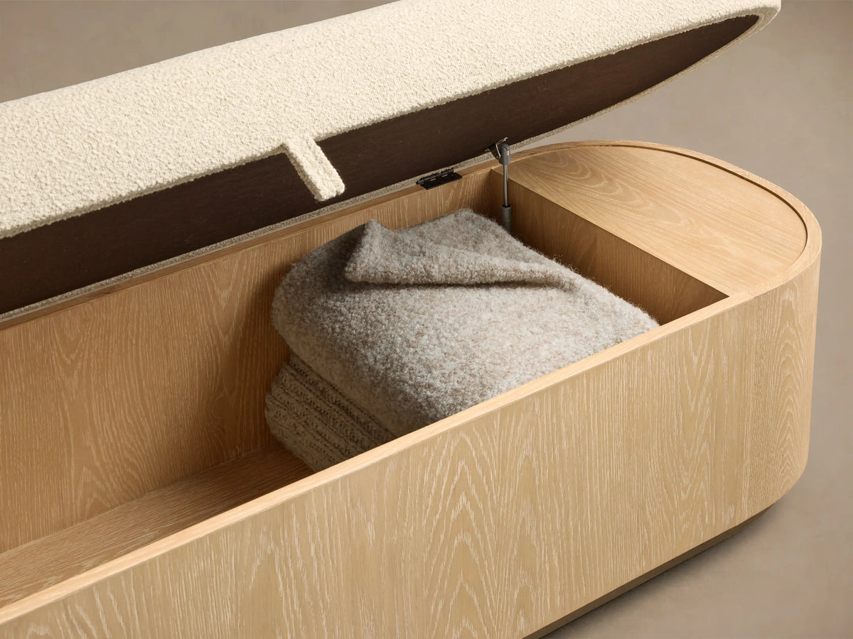 Front view of the Sand finish Caden Storage Bench, featuring oak veneer, cream textured fabric cushion, and brushed nickel plinth.