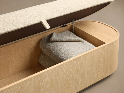 Front view of the Sand finish Caden Storage Bench, featuring oak veneer, cream textured fabric cushion, and brushed nickel plinth.