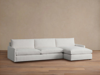 Alt text: Kipton Two-Piece Chaise Sectional in light fabric, featuring three-seat cushions and a right-side chaise, on a wooden floor.