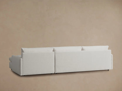 The image shows the back view of the Kipton Two-Piece Chaise Sectional in a light fabric, emphasizing its modern, rectangular shape against a neutral background.