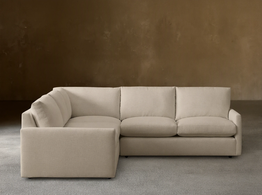 Kipton Three-Piece Corner Sectional in beige fabric shown in a left-facing orientation on a wooden floor, set against a plain taupe wall.