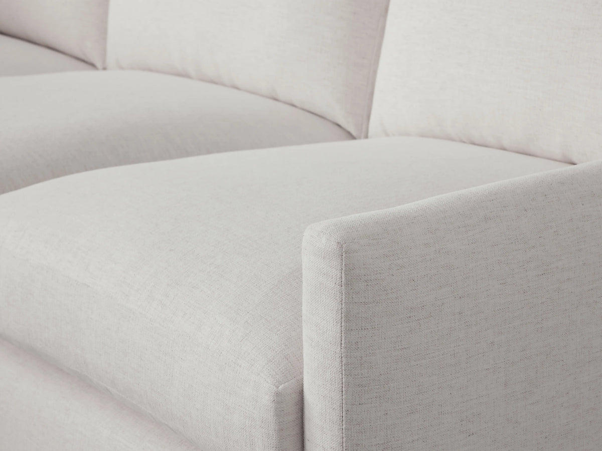 Kipton Two-Piece Chaise Sectional in a light neutral fabric. Features a left chaise, three seat cushions, and three back cushions. Placed on a wooden floor.