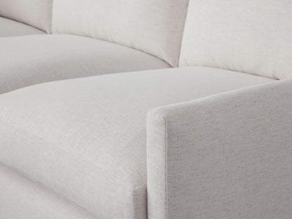 Kipton Two-Piece Chaise Sectional in a light neutral fabric. Features a left chaise, three seat cushions, and three back cushions. Placed on a wooden floor.
