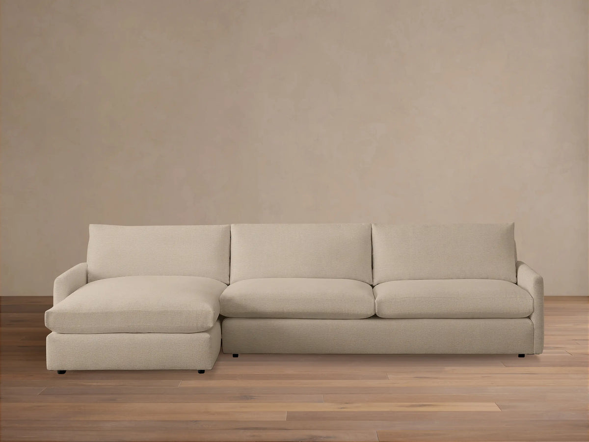 Kipton Two-Piece Chaise Sectional in a neutral beige fabric, featuring a left-side chaise and right-side loveseat on a wooden floor.