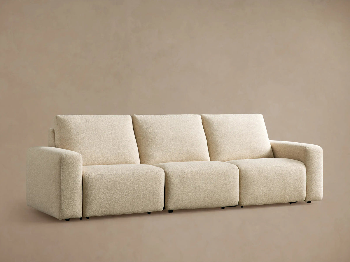 Brennan Three-Piece Motion Sofa, light cream textured fabric, modern design with blocky arms & cushions, on wood floor.