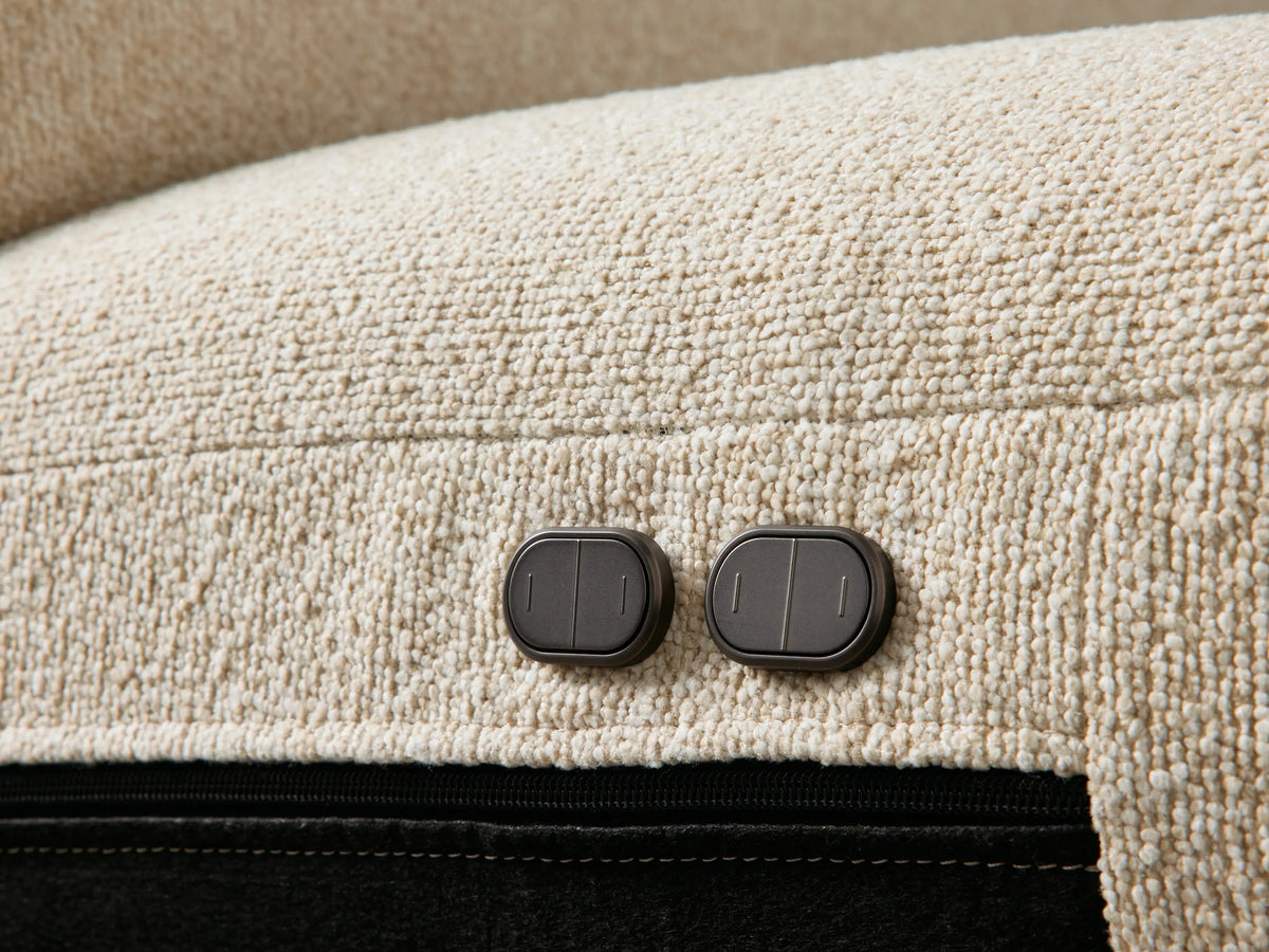 Brennan Motion Sofa, close-up of light beige textured fabric, plush seat/back cushions, and armrest. Footrest partially visible.