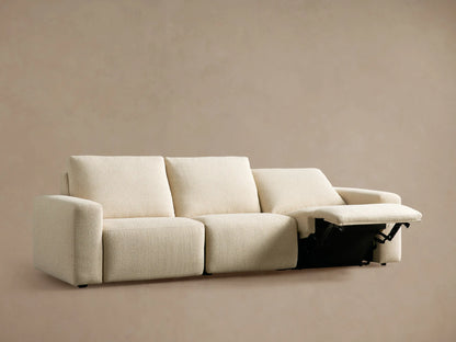 Brennan Three-Piece Motion Sofa in light beige fabric, with two footrests extended, against a plain tan wall.